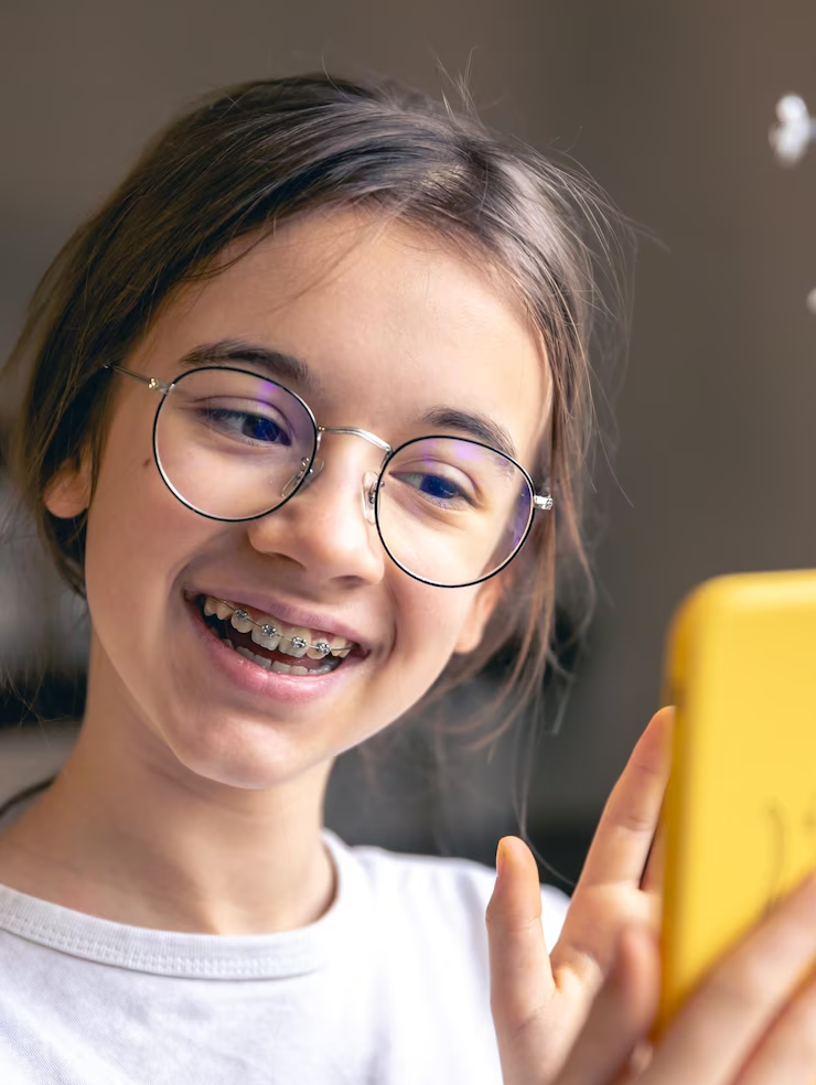 A teenage girl in glasses and braces communicates via video call